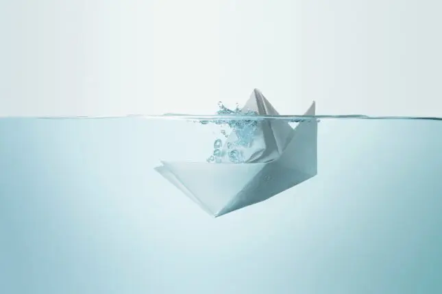 Illustration of a paper boat slowly sinking beneath water