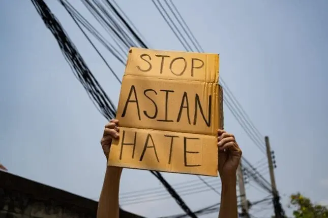 Hands holding a sign that reads "Stop Asian Hate"