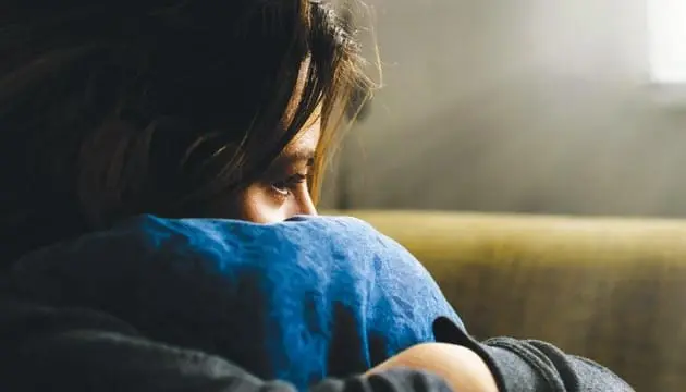 A sad woman holds a pillow to her chest