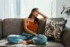 A young woman sits on a couch looking disappointed