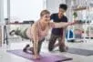 A yoga trainer helps a woman with a pose