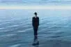 A man in a suit stands in a body of water