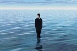 A man in a suit stands in a body of water