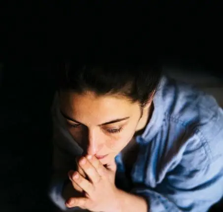 A woman holds her hands to her mouth contemplatively