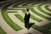 A woman in academic regalia walks a labyrinth