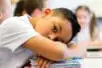 A young boy with his head on his desk | iStock/DG Images