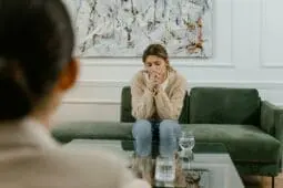 a sad woman sitting on a couch in front of her therapist | Photo by Mart Production/Pexels