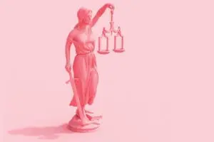 Lady justice holding scales and sword on pink background