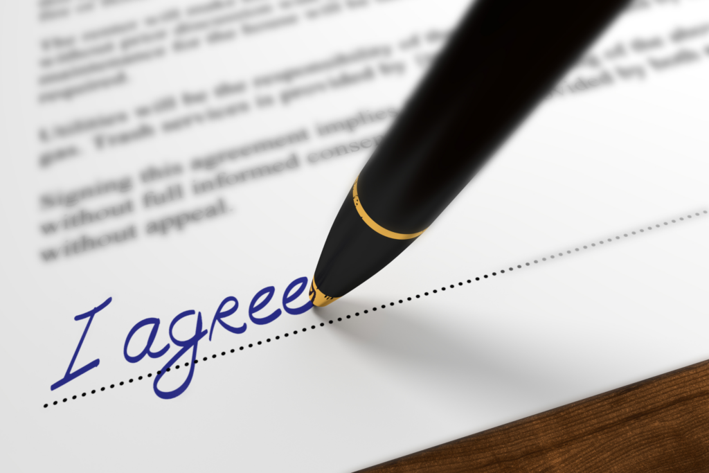 A pen and the words "I agree" handwritten on a dotted line on a document