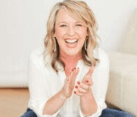 Seated woman in jeans clapping hands and smiling.