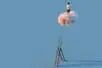 A figure stands atop a pink cloud, having left a tall ladder behind