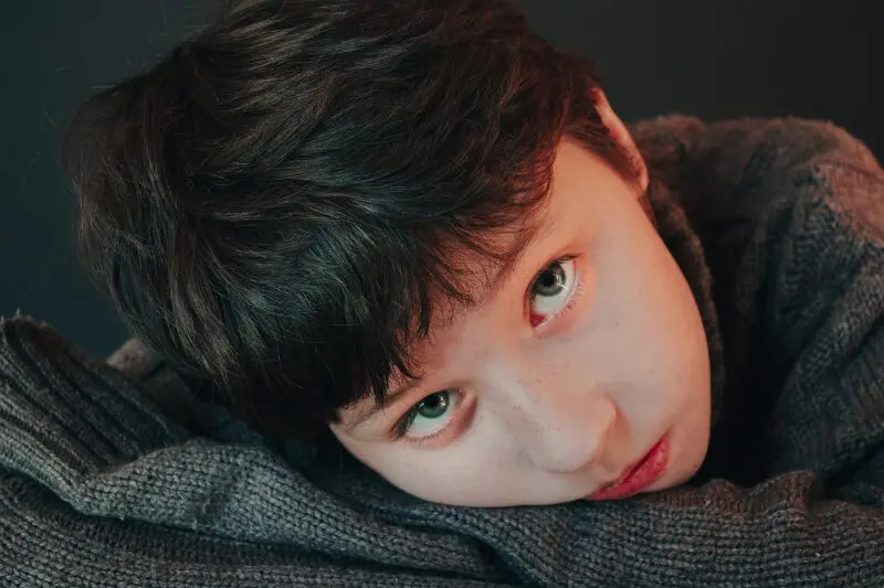 A child leans on his arms and looks up at the camera