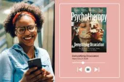 A woman looks at her phone on the left side of the image and smiles while the right side of the image displays the cover of this month's issue with a play button beneath it