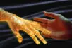 A human hand reaches out to one made up of glowing golden bands