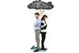 A couple stands back to back, upset and under a storm cloud