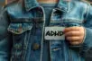 A child holds an a label reading ADHD in front of their chest