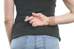 A woman stands with her fingers crossed behind her back