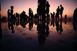 Silhouettes of people standing in front of a sunset