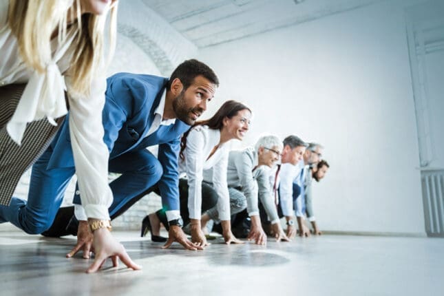 A group of business-people kneeling at the start of a race