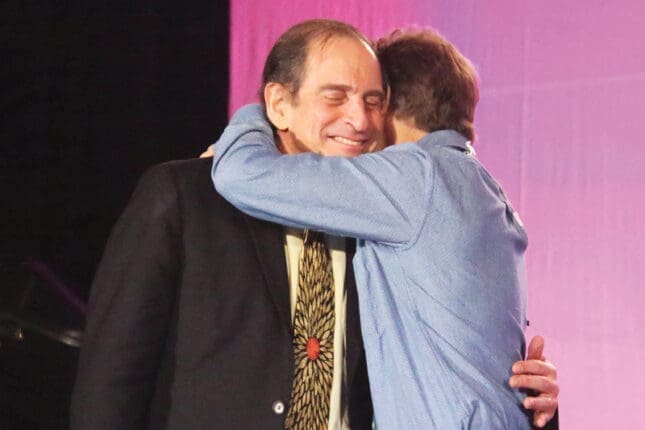 Rich Simon and Dan Siegel hug onstage