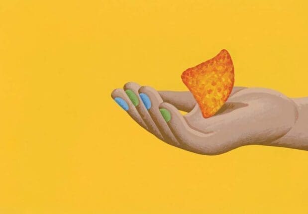 A hand holds a tortilla chip