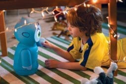 A boy interacting with a small blue robot