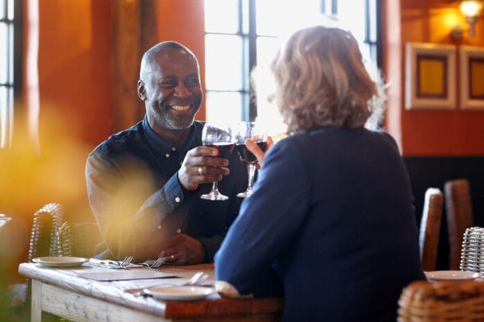 A middle-aged man and women clink wine glasses