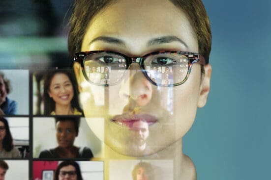 A woman looks at a screen of faces on a video call