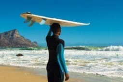 A surfer with a board on his head standing on the beach