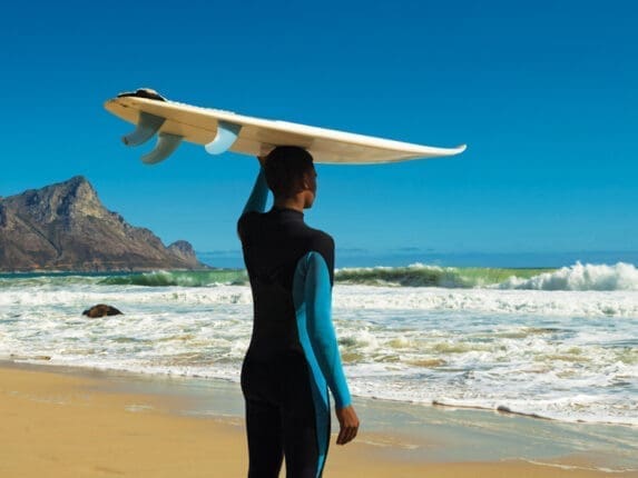 A surfer with a board on his head standing on the beach