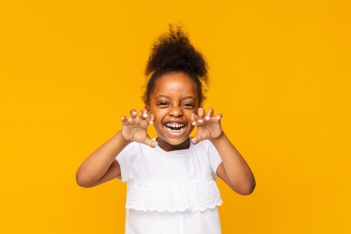 A young girl holds her hands up playfully