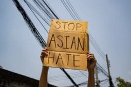 Hands holding a sign that reads "Stop Asian Hate"