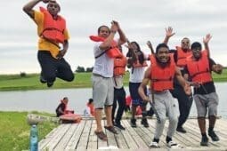 A group of kids in life vests play on a dock