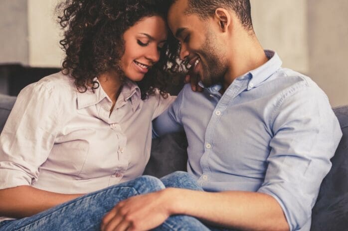 A man and a woman cuddling on a couch