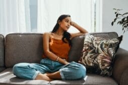 A young woman sits on a couch looking disappointed