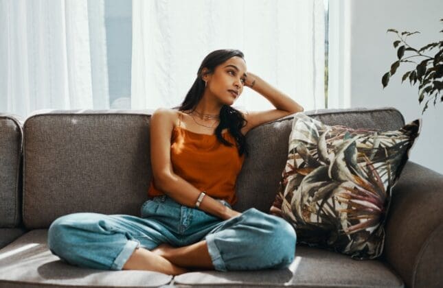 A young woman sits on a couch looking disappointed