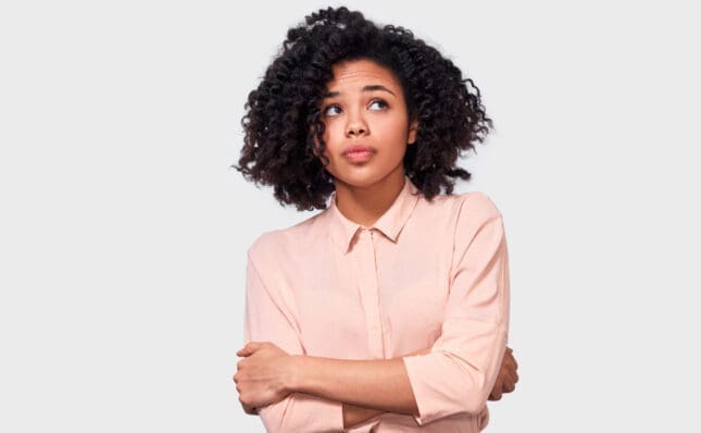 A Black woman stands with her arms crossed