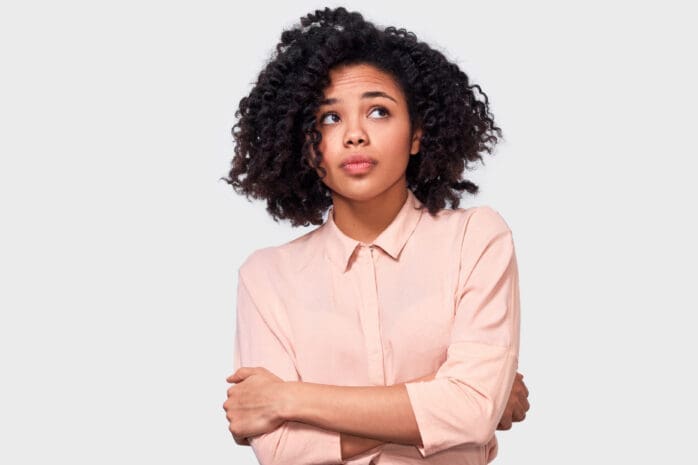 A Black woman stands with her arms crossed