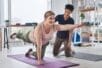 A yoga trainer helps a woman with a pose