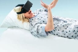 A woman lying in bed with a VR headset on