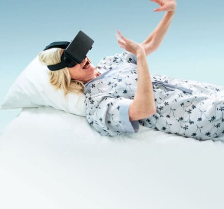 A woman lying in bed with a VR headset on