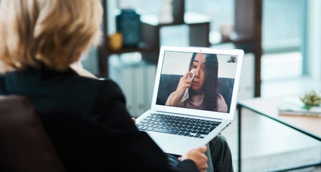 A woman cries onscreen as her therapist looks on