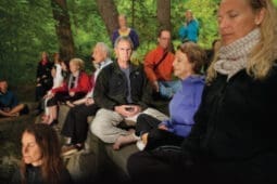 A man sits cross-legged amongst a crowd