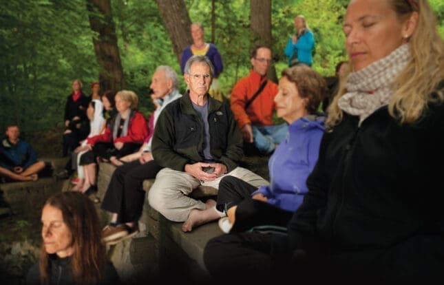 A man sits cross-legged amongst a crowd