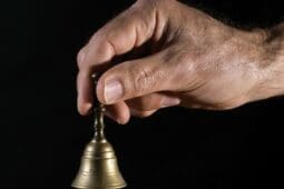 A hand holding a small bell