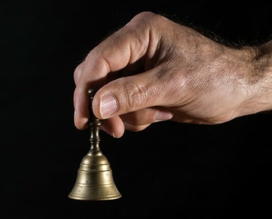 A hand holding a small bell