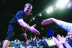 A man on stage holds his hand out to someone in the crowd