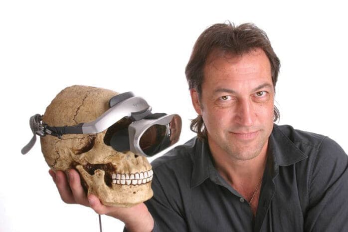 A man holds a skull with a VR headset on it