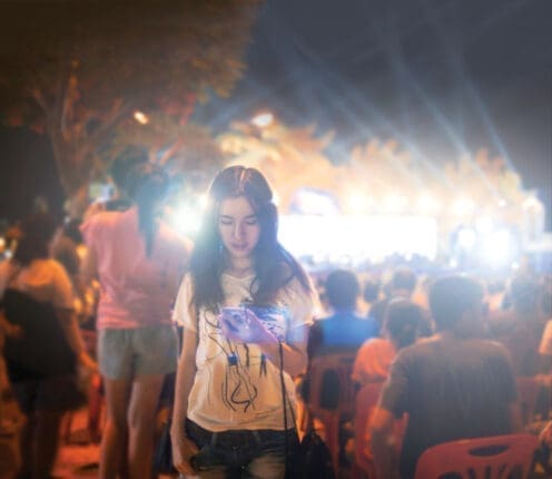 A young or teen girl looking dejected at the edge of a large crowd