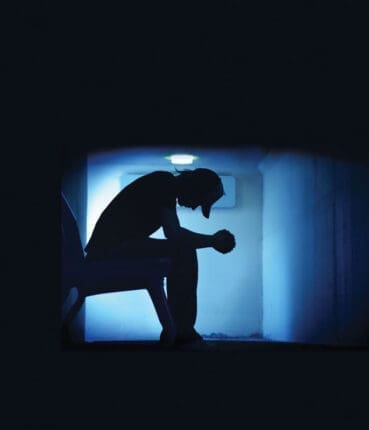 A teenager looks at the floor with his elbows on his knees